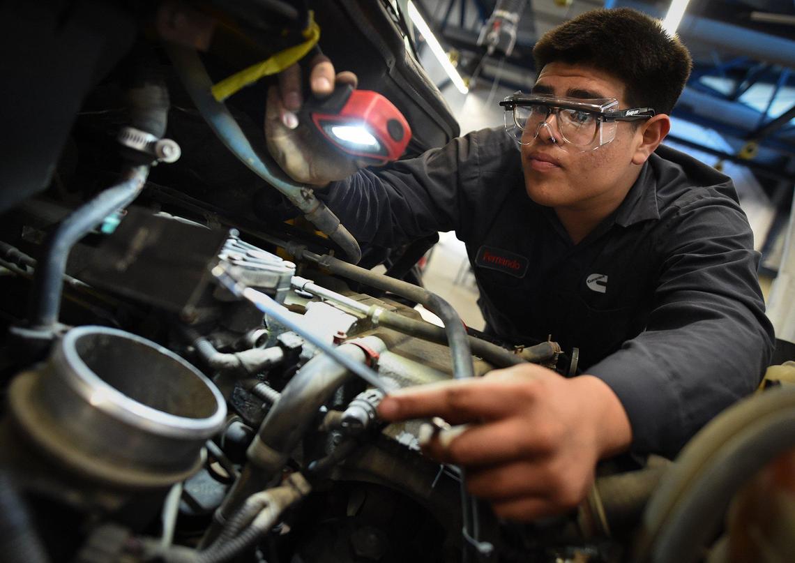 Duncan Polytechnical High School senior Fernando Valera works under the hood of a commercial heavy duty truck used for training in the Heavy Duty Truck pathway at the school. Outside of school, Valera works as a truck technician for a company that expects to hire him after graduation.