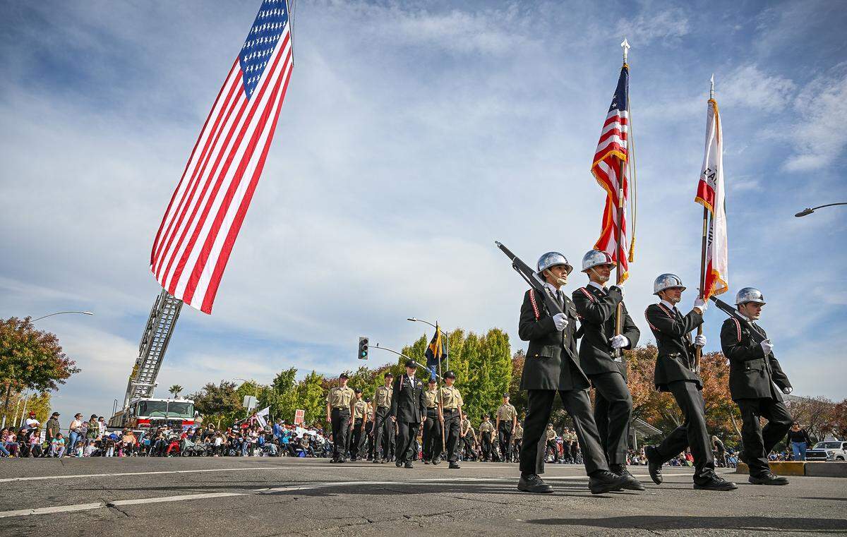 Members of the California Cadet Corps, Fifth Brigade march below a giant American flag while making the turn onto Fresno Street during the Central Valley Veterans Day Parade in downtown Fresno on Tuesday, Nov. 11, 2025. 