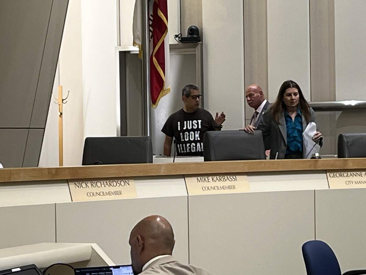 Fresno City Councilmember Miguel Arias, left, talks to Mayor Jerry Dyer while wearing an “I just look illegal” shirt at the June 16, 2026, Fresno City Council meeting.