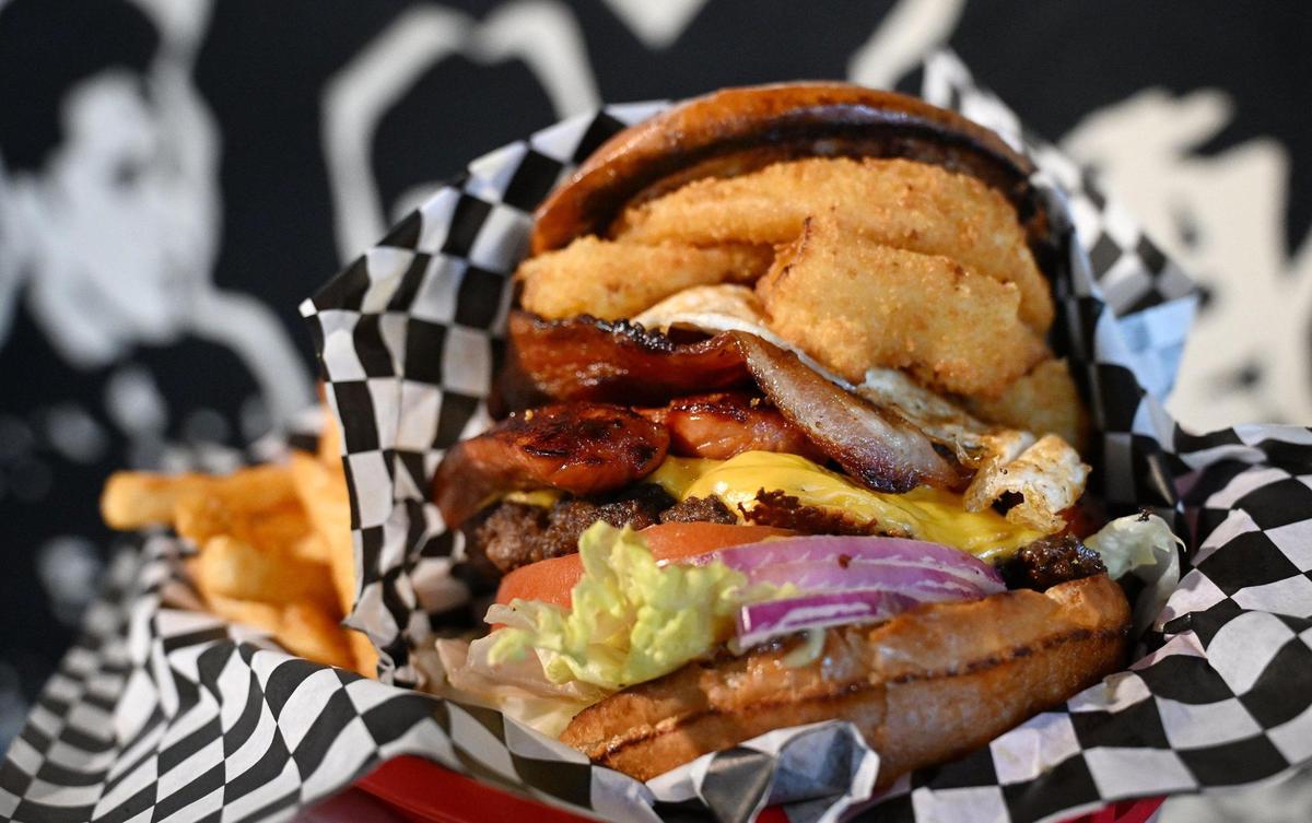 The Bernie Mack Slap burger with fries features over 5 inches of fillings including thick-cut bacon, onion rings, fresh onions and a fried egg is one of the featured burgers from Take 3 x Grumpy Burger Lady’s. The restaurant on Fulton Street in downtown Fresno, California, re-opened Jan. 27, 2025.