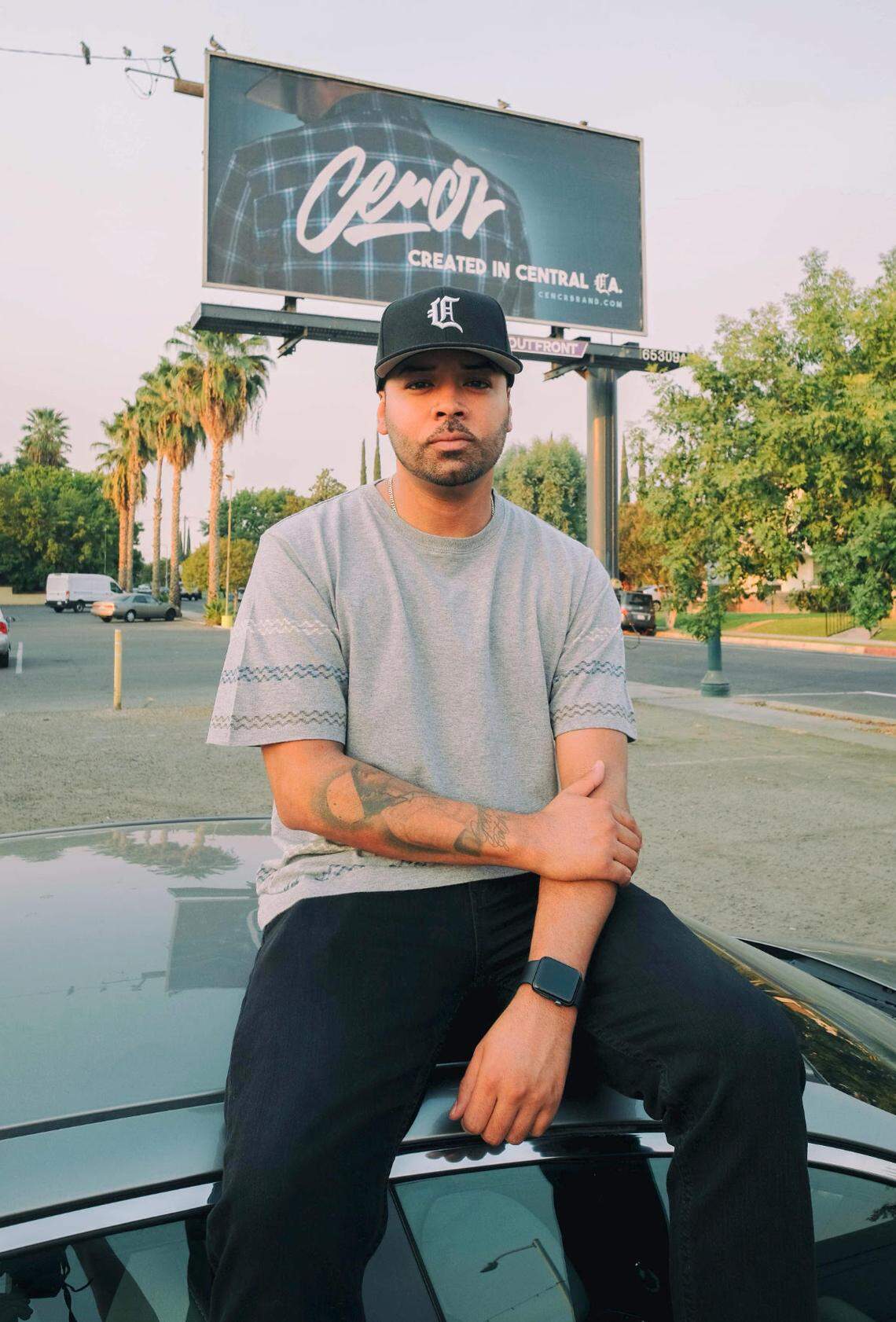Dorian “Cuddie” Castro poses in front of a billboard promoting his new clothing line, CENCR.