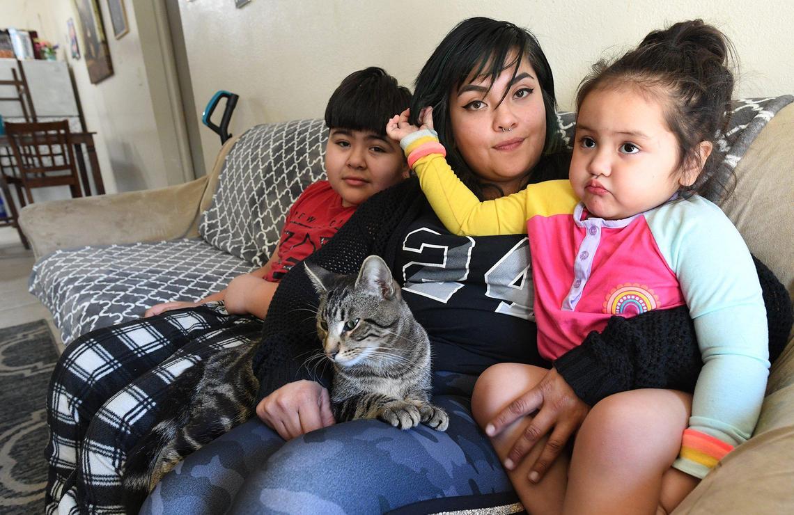 Manchester Arms Apartments resident Melissa Tepezano in her apartment with her children, Jeremy, 10, Winter, 3, and cat Tiger, Feb. 17, 2021. She has had issues with management not responding to problems, such as a recent flood in the apartment from an apparent broken pipe behind a wall. She had to throw out her and her children’s clothing, stuffed toys, and her mattress. Another time, her garbage disposal stopped working. Her father, who lives in the complex and is legally blind, worked to get it running. Her heater/AC unit was out for three months, also.