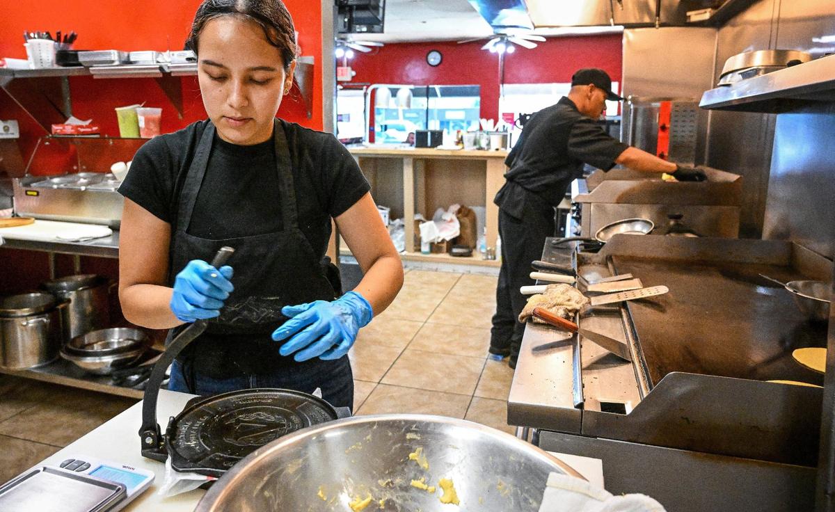 Yamii Mondragon presses homemade corn tortillas for the griddle while Armando Juarez grills up an entree at Fuego Taqueria y Restaurante in Fresno on Thursday, Aug. 22, 2024.