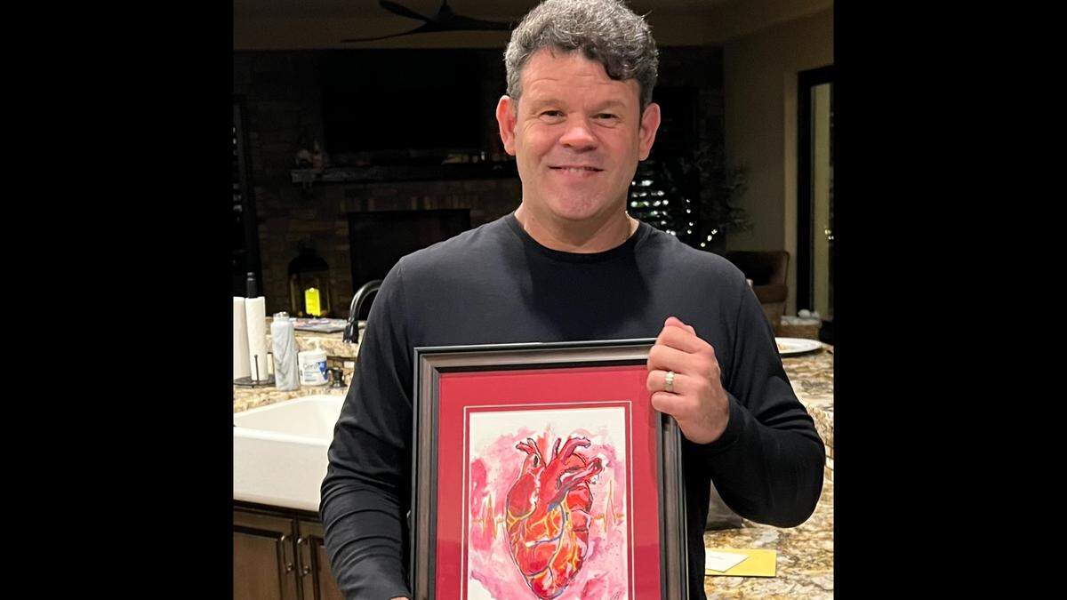 Dr. Alfred Valles holds a painting of a heart that was given to him as a birthday present in November 2022 by one his patients.
