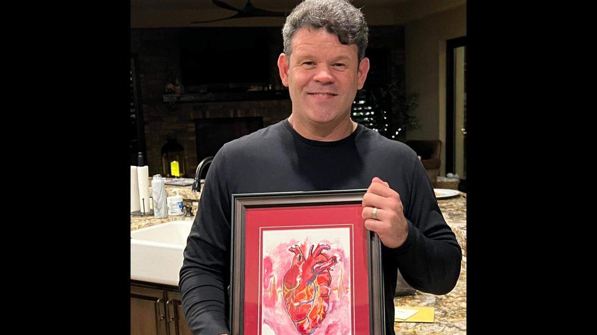 Dr. Alfred Valles holds a painting of a heart that was given to him as a birthday present in November 2022 by one his patients.