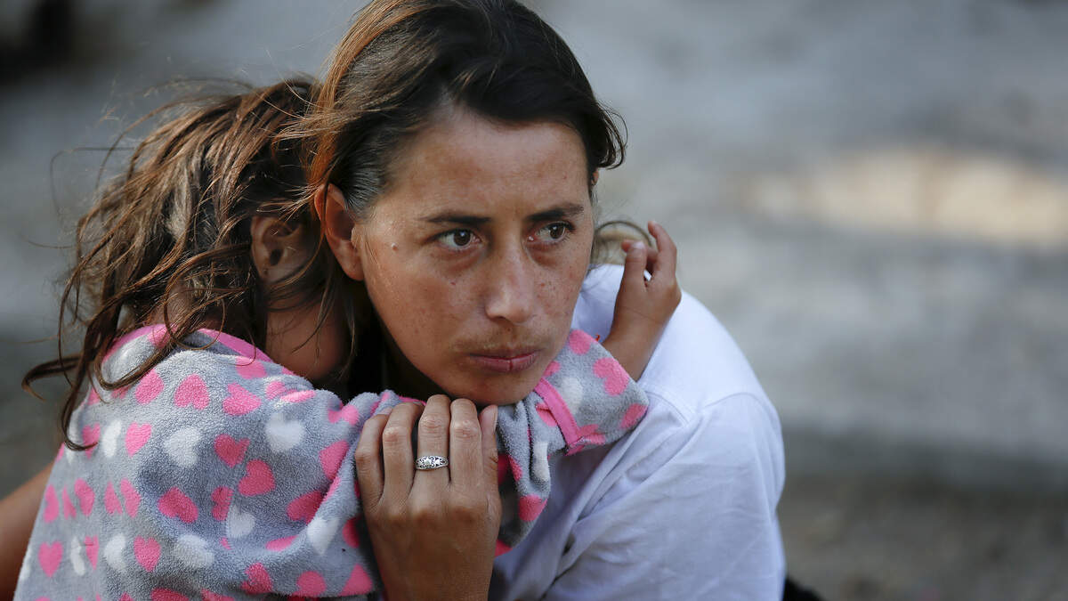 A woman and her daughter wait just outside the temporary shelter set up at Unidad Benito Juarez in Tijuana where refugees are temporary sheltered.