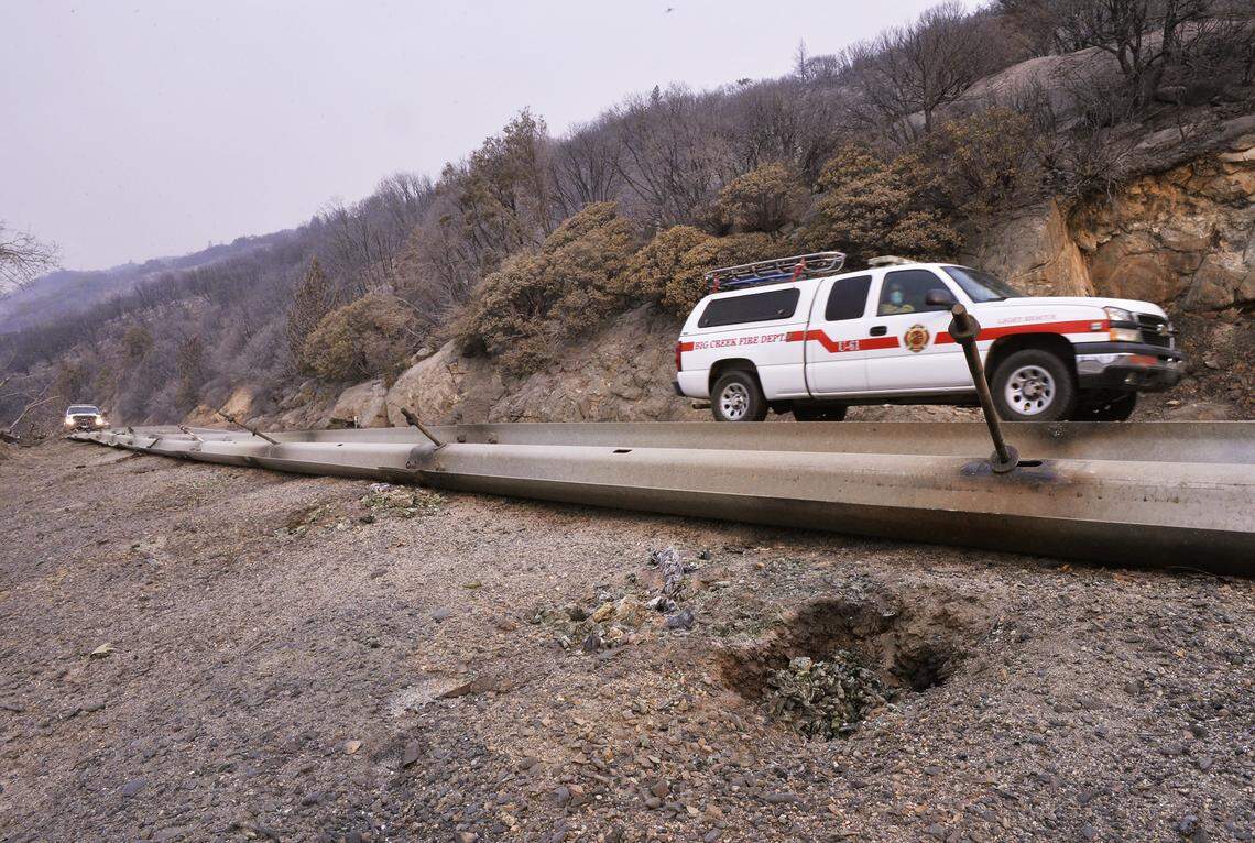 A Big Creek Fire department truck passes by highway guard railing, fallen after wooden support posts were burned by the Creek Fire along Highway 168 between Tollhouse and Cressman on Wednesday, Sept. 9, 2020.