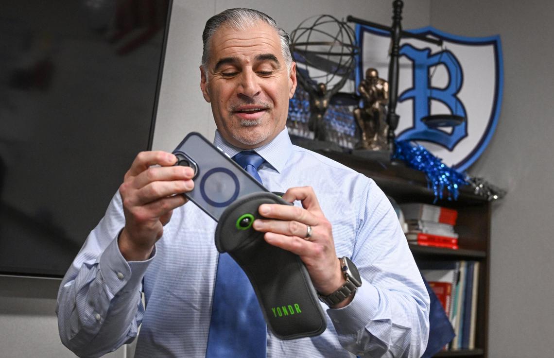 Bullard High School principal Armen Torigian demonstrates how Yondr pouches are used at the school on Monday, Jan. 22, 2024. Phones go into the pouches and stay locked inside until after the school day ends when they can be unlocked with a magnetic device.