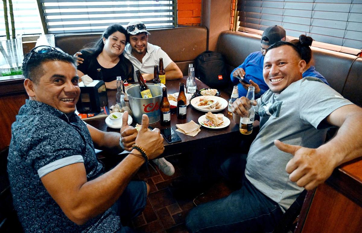 Jesús Molinares, izquierda, y Jedlis Joel Vidaurre, derecha, dan su aprobación con el pulgar hacia arriba mientras comen y beben con amigos en El Godinazo Fresno Centro Botanero, ubicado en Belmont, en el centro de Fresno, el viernes 23 de junio de 2023.