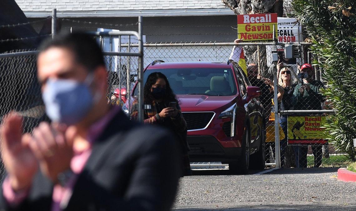 Protestors calling for the recall of Gov. Gavin Newsom shout from behind a fence during his press conference at the Fresno Fairgrounds, Feb. 10, 2021.