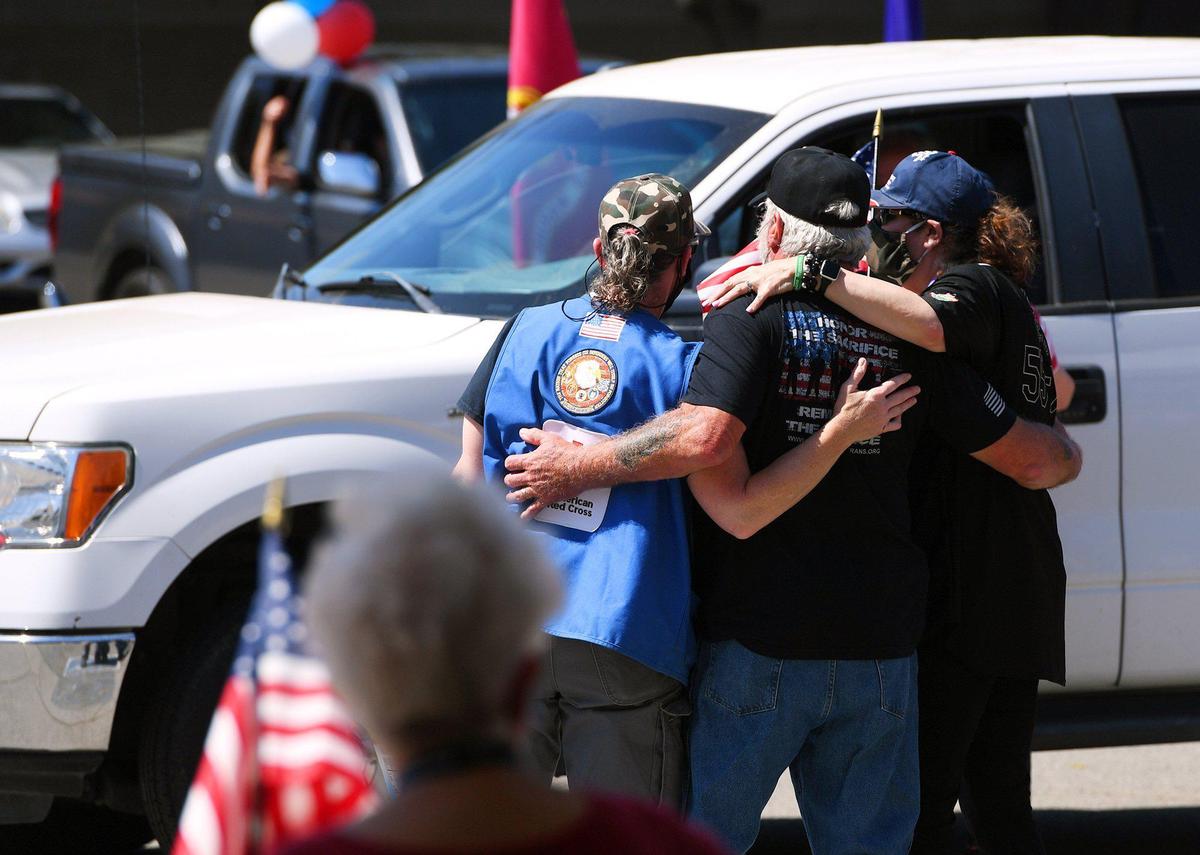 Sarah Monroe, left, John “Top” Schuler, center, and Mary Golden Placido, right, dance to a Creedence Clearwater Revival song as cars drive through a ceremony honoring service men and women in observance of National Vietnam War Veterans Day on Monday afternoon, March 29, 2021, at the Fresno Vet Center at Shaw Avenue and Sixth Street.