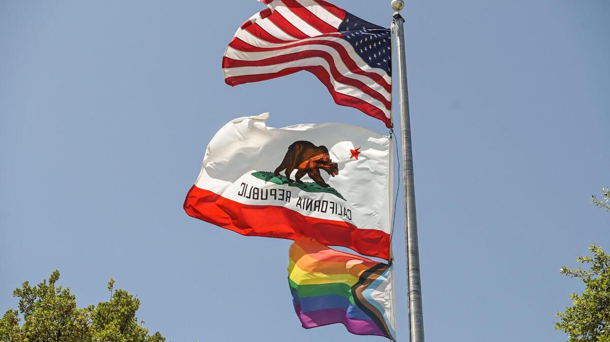 A Pride flag flies along with the American and California flags on the flag pole at Clovis Community College.