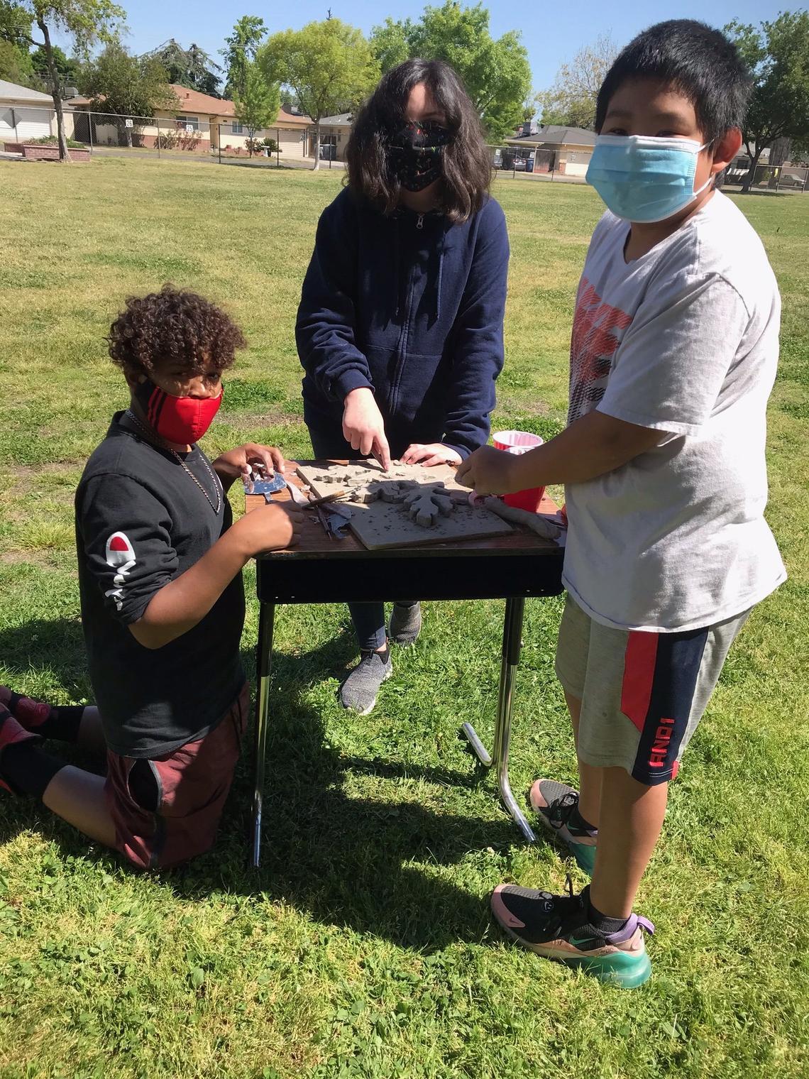 Manchester GATE sixth grade students work on their porcelain-mix ceramic leaves to be added to the valley oak mural being put together by Fresno artist David Roberts.