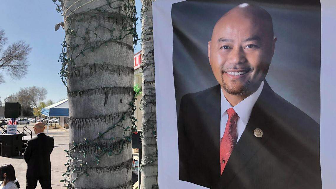 A poster of Clovis City Council Member Vong Mouanoutoua as Mouanoutoua, at left, listens to speakers during a rally in Clovis on Saturday, Feb. 27, 2021 to support his re-election.