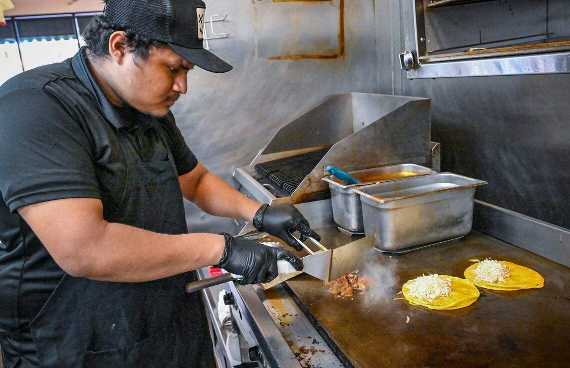 Alex Mojica works on a pair of birria tacos with cheese and consome at Mex Sabor Cocina Mexicana, a New Mexican restaurant in Fresno's River Park shopping center. 