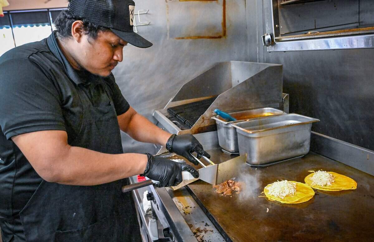 Alex Mojica works on a pair of birria tacos with cheese and consome at Mex Sabor Cocina Mexicana, a New Mexican restaurant in Fresno's River Park shopping center.