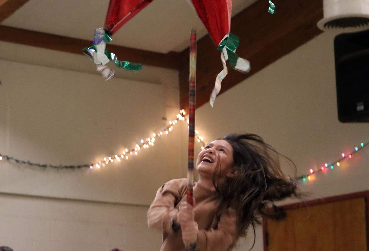 A young girl takes a swing at a piñata during the posada hosted by St. Anthony Mary Claret Church in southeast Fresno on Dec. 18, 2023.