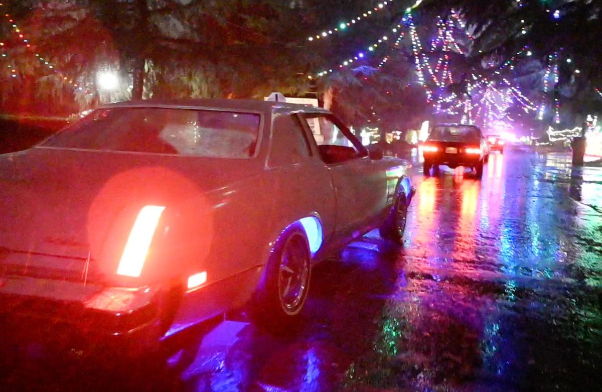 Classic cars drive along rainy North Van Ness Boulevard as a part of the opening ceremony for the 100th year of Christmas Tree Lane half an hour before the official 6 p.m. opening for the public Thursday, Dec. 1, 2022 in Fresno. Classic cars of all styles helped usher in the annual event. A limited supply of commemorative T-shirts and hoodies celebrating 100 years will be for sale, according to organizers.