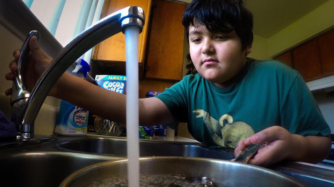 Nine-year-old Jose Hernandez draws tap water June 17, 2020, in his Earlimart home for dishwashing – one of the few purposes his family uses the city’s well water for – because of lingering fears of contamination of the groundwater.