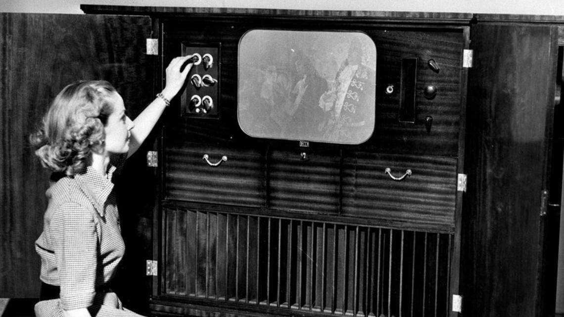A viewer adjusts the contrast on a black-and-white television.