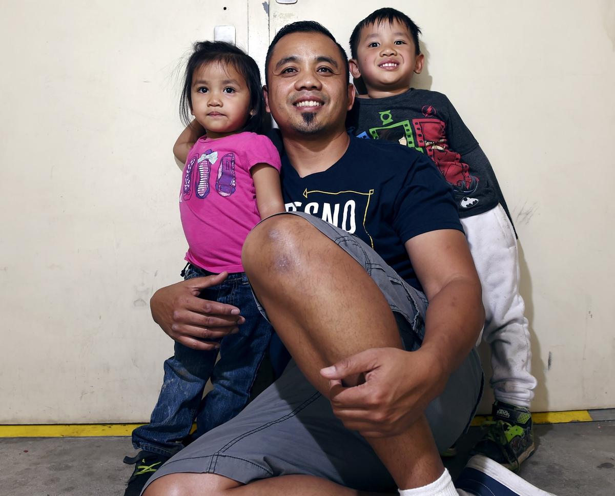 Vanna In, center, sits with two of his three children, Thanny In, 2, left, and Jeevin In, 4, right, Friday, May 4, 2018 in Fresno.