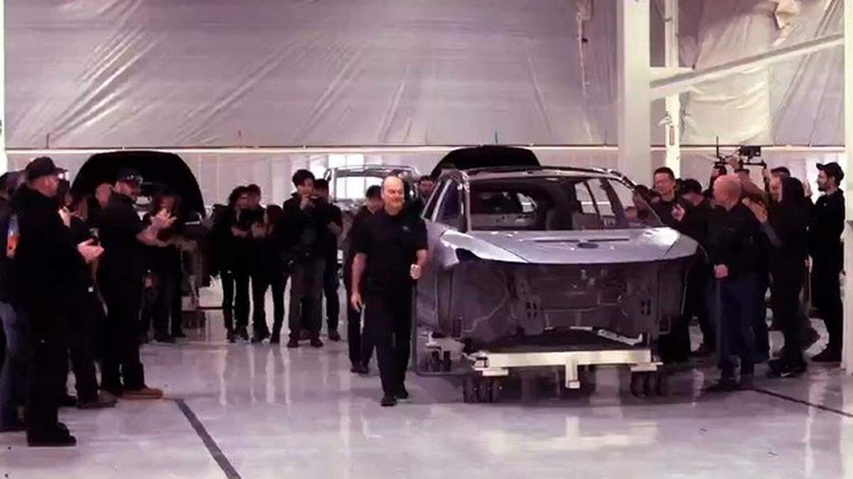 Company executives from Faraday Future use a cart to roll out the body of the first production unit of its FF 91 Futurist, an all-electric, luxury crossover SUV, from the paint shop of the company’s factory in Hanford, CA, on March 29, 2023.