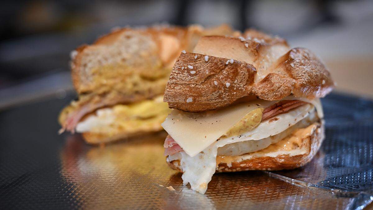 A freshly made Oktoberfest egg sandwich with eggs, ham, bacon, and Swiss cheese, topped with beer cheese shmear and a drizzle of mustard on a pretzel bagel is served up at Einstein Bros Bagels, which is now open near the Fresno Convention & Entertainment Center in downtown Fresno.