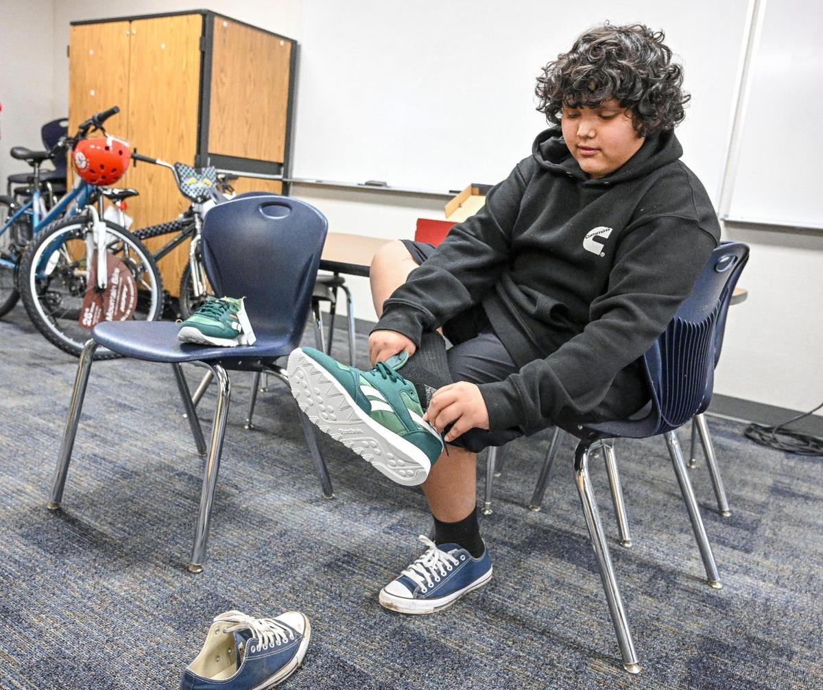 Giovanni Ruiz Gonzalez tries on a new pair of shoes that were giving to him through the community school program at Jackson Elementary School on Wednesday, Dec. 18, 2024.
