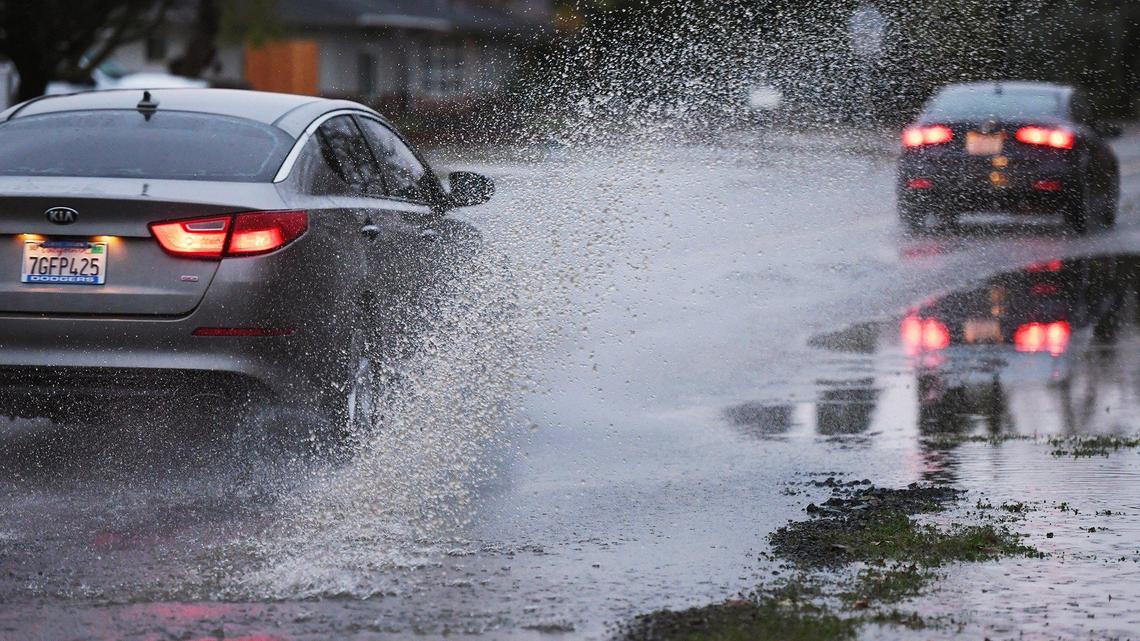 Vehicles splash through standing water along Fruit Avenue north of Ashlan Avenue Thursday evening, Dec. 23, 2021 in Fresno.