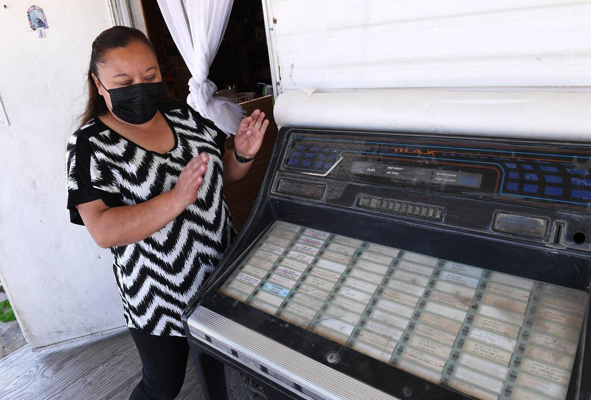 Claudia Cruz stands next to a jukebox outside the family home’s front door which her husband Pedro Cruz Mendoza used to play and dance to at family gatherings, seen Tuesday, April 6, 2021 in Lemoore. Pedro Cruz Mendoza died from COVID-19 in March.