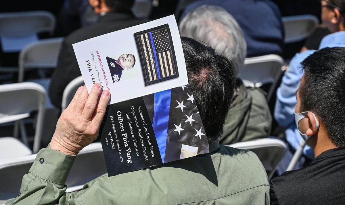 An attendee shades himself with a program during a dedication ceremony for the Fresno Police Department’s southeast district station, which is being named in honor of Phia Vang who died in an off-duty car crash, on Friday, April 15, 2022.