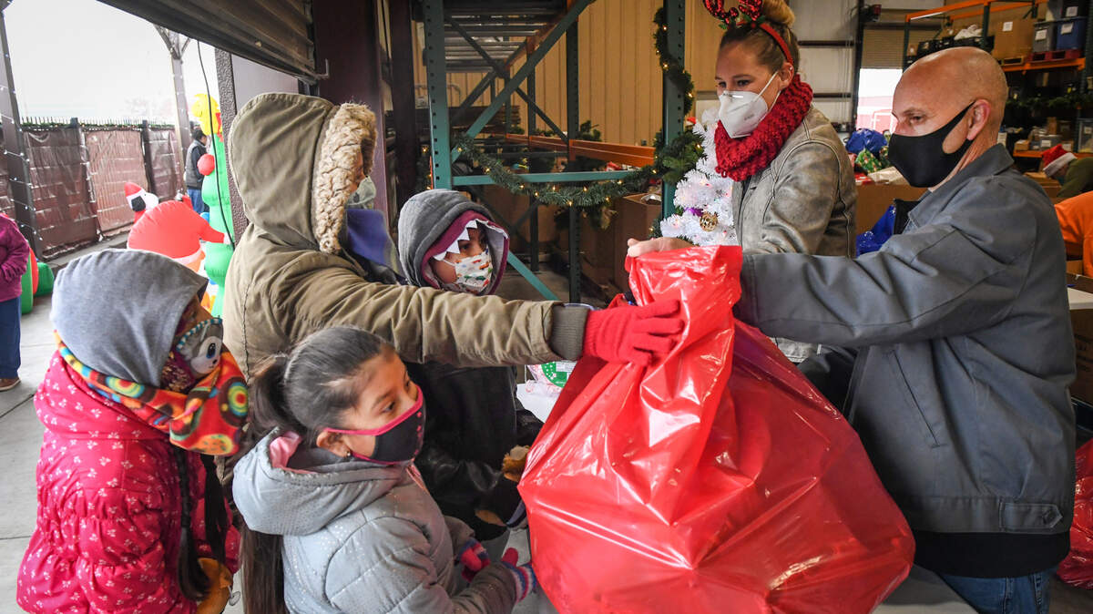 Poverello House staff members Cory Amoroso and Abigail Nolte hand out bags of gifts to families at the Poverello House’s annual Christmas Eve gift giveaway for children of local families affected by homelessness and poverty, on Thursday, Dec. 24, 2020. More than 7,000 toys purchased by the community and local organizations and businesses through various toy drives. Due to the pandemic, this year’s event was held outside with COVID-19 protocols in place to keep everyone safe. A “Tunnel of Christmas” allowed kids to experience a festive holiday atmosphere and Santa was on hand to brighten smiles and bring cheer.