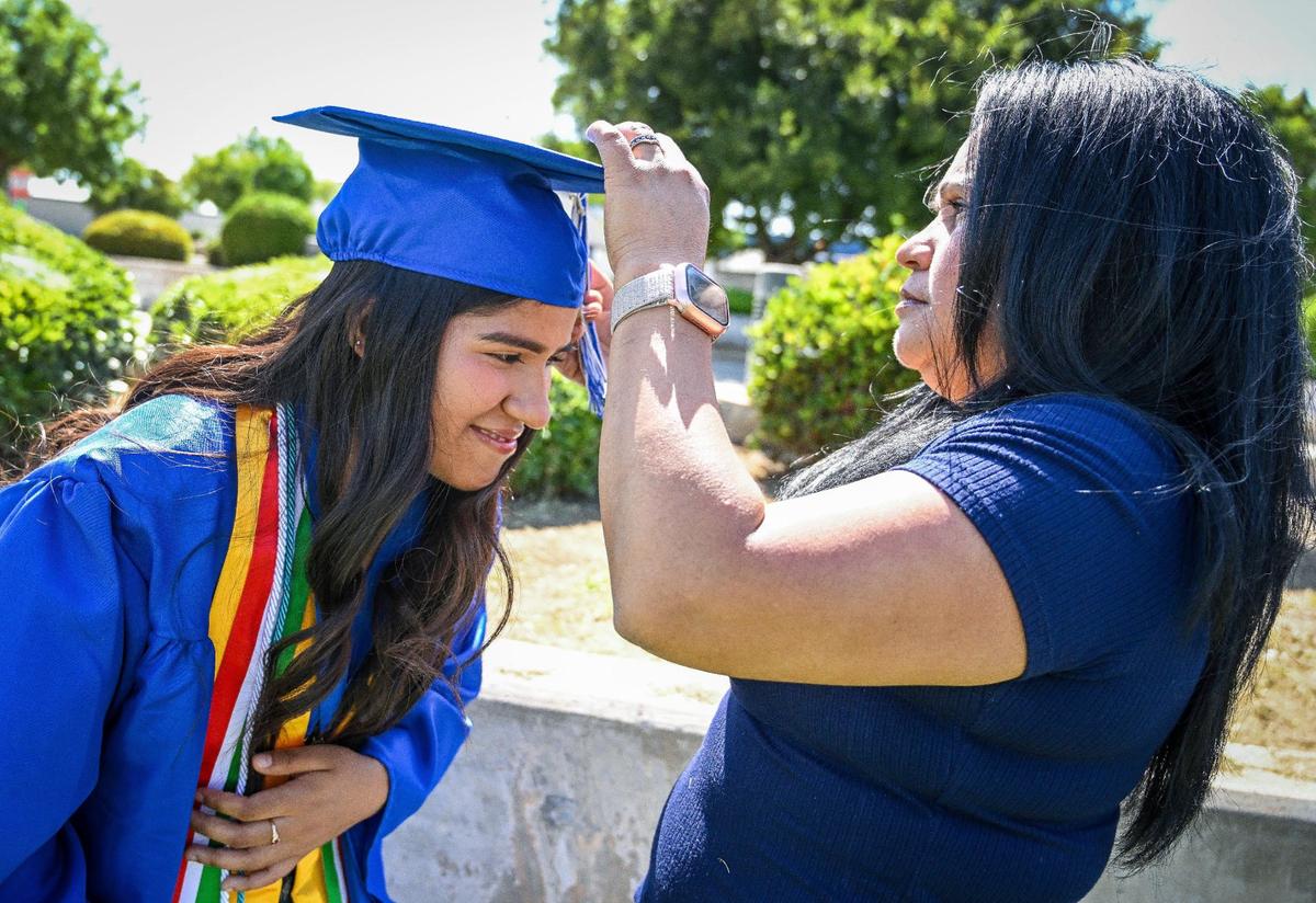 Anasol Martínez-García, a Farmersville High School Horatio Alger scholarship recipient, has her mother Irma Garcia help her with her tassel while taking pictures in her graduation cap and gown at the school on Tuesday, May 21, 2024.