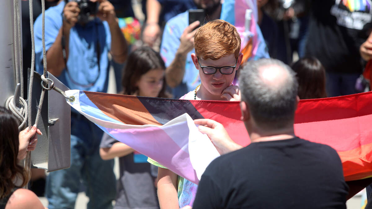 Fresno’s Kyan, 11, a contributing Dear Freedom Writer, helps raise the Pride Flag during a noontime ceremony at Fresno City Hall on June 10, 2022.