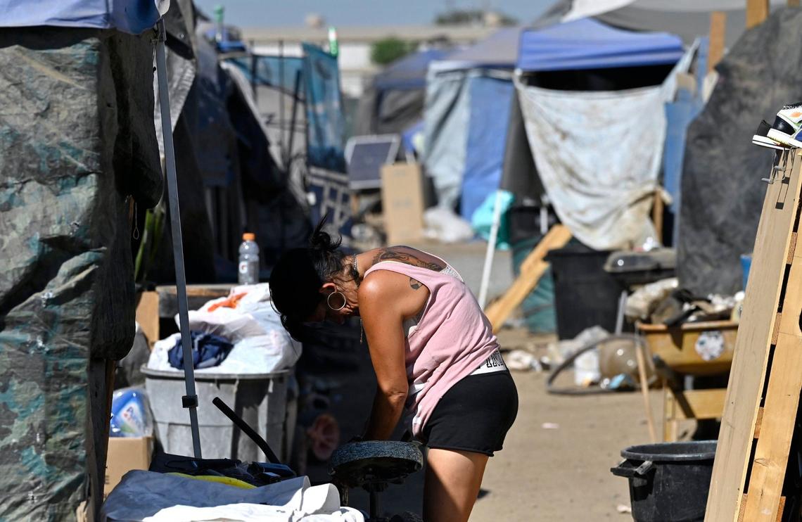A woman locks her bike at a campsite as we look inside the City of Tulare’s temporary encampment located at the south end of town Tuesday, Sept. 10, 2024.