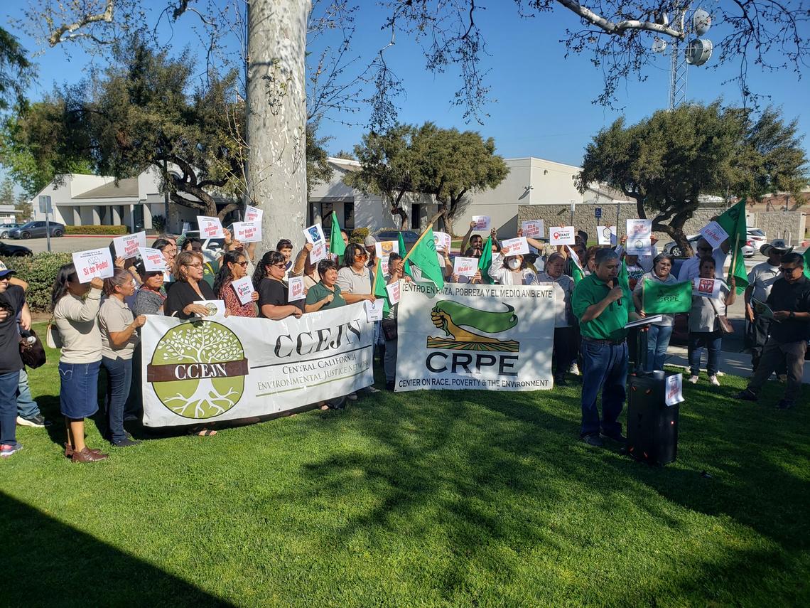 Representatives from Central California Environmental Justice Network hold a sign during a press conference about the new online pesticide notification system on March 24 in Shafter, CA.