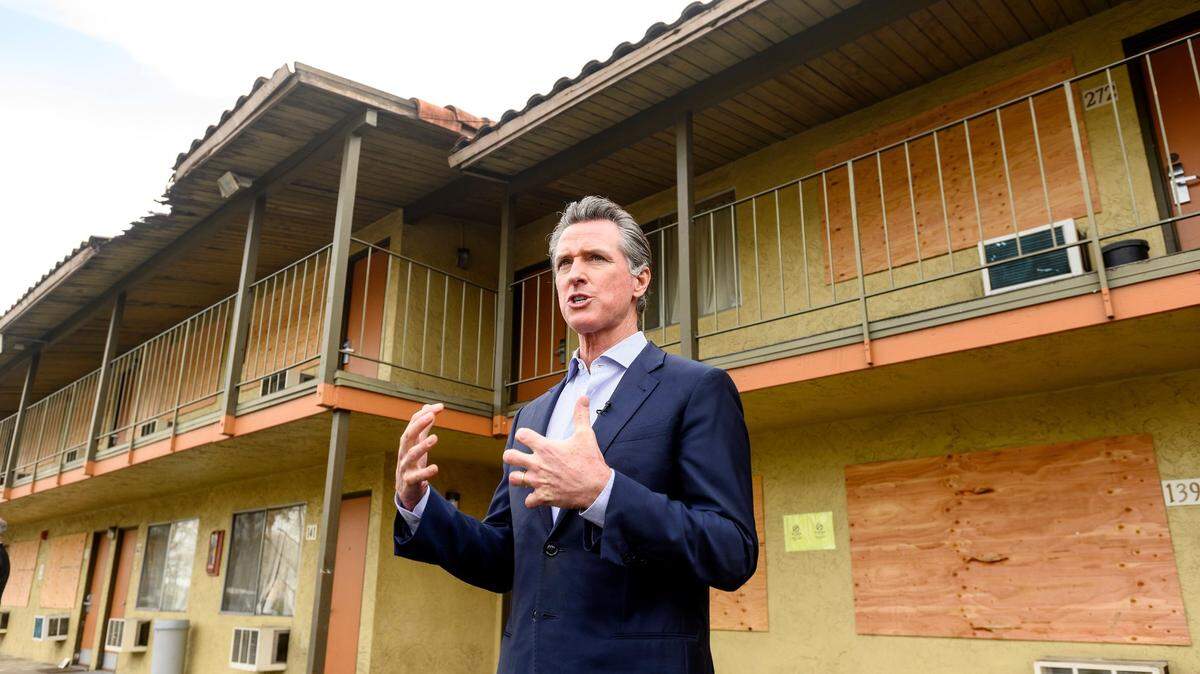 Gov. Gavin Newsom speaks with reporters while touring a Bay Area motel being converted to housing for homeless people in January.