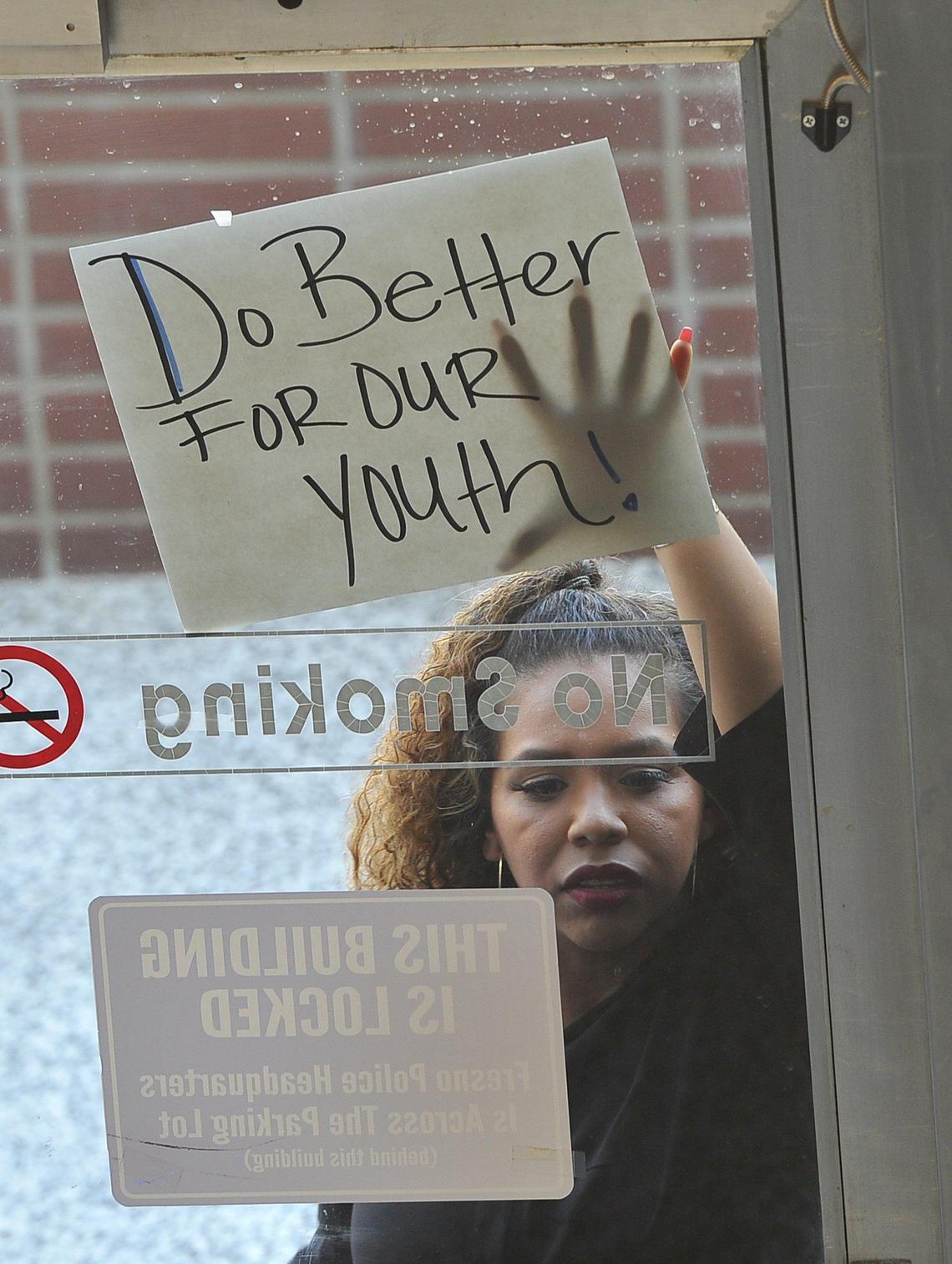 A protester stands at the locked doorway of the City Hall Annex building where new Acting Police Chief Andy Hall was being introduced at a press conference, Friday morning.
