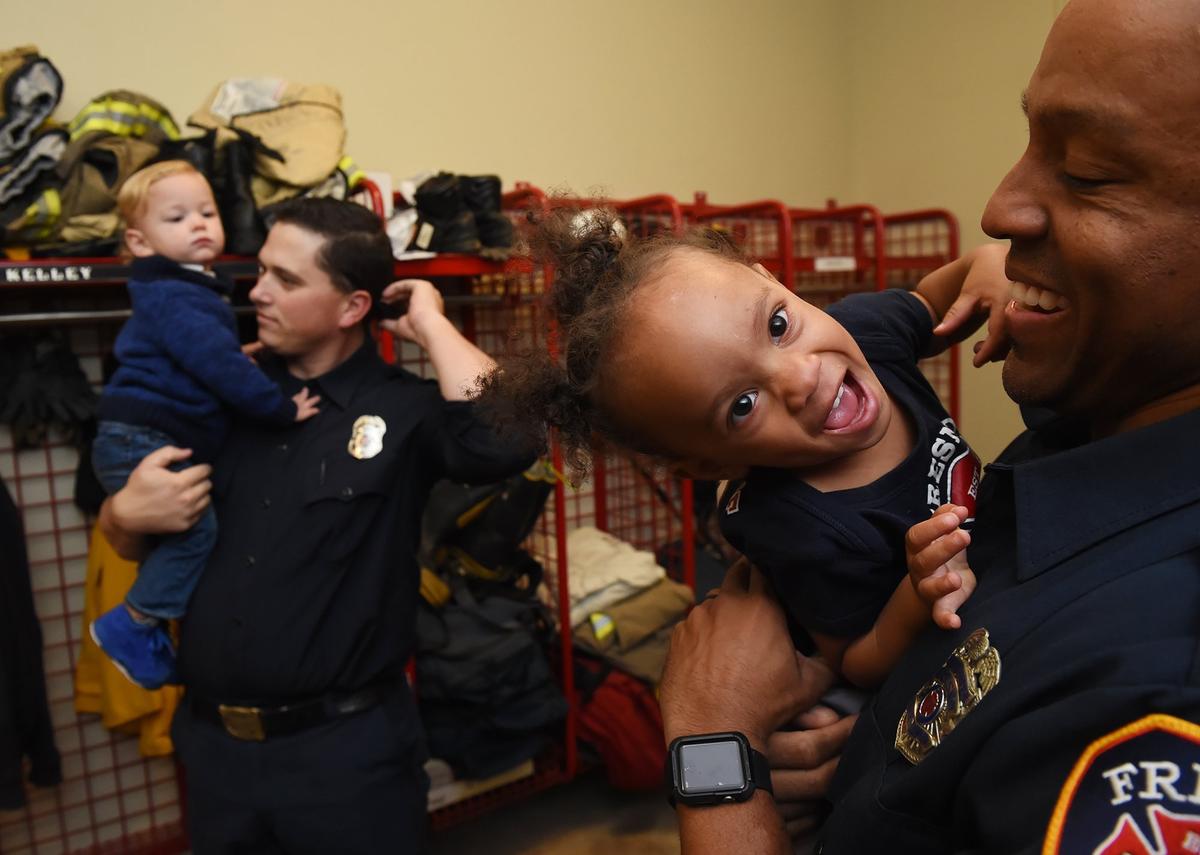 Myla, 19 months old, right, plays in her father Michael McIntyre’s arms, while Jett Henry is held in his father Josh Henry’s arms at Fresno Fire Station 3 on Monday, Nov. 12, 2018 in downtown Fresno.