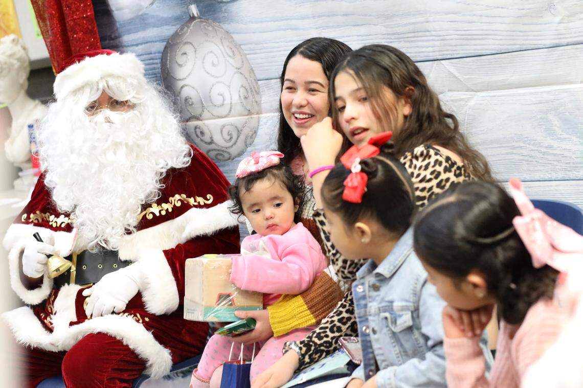 Isela Molina con sus hijos y Santa sonríe durante el evento de Navidad de la Familia Migrante 2023 que se llevó a cabo en la biblioteca de la Firebaugh High School el 13 de diciembre.