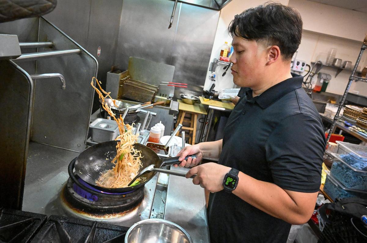 Co-owner Tito Thepkaysone cooks up chicken pad thai in the kitchen during the grand-opening event at Satay Thai Kitchen and Bar in north Fresno on Thursday, May 8, 2025.