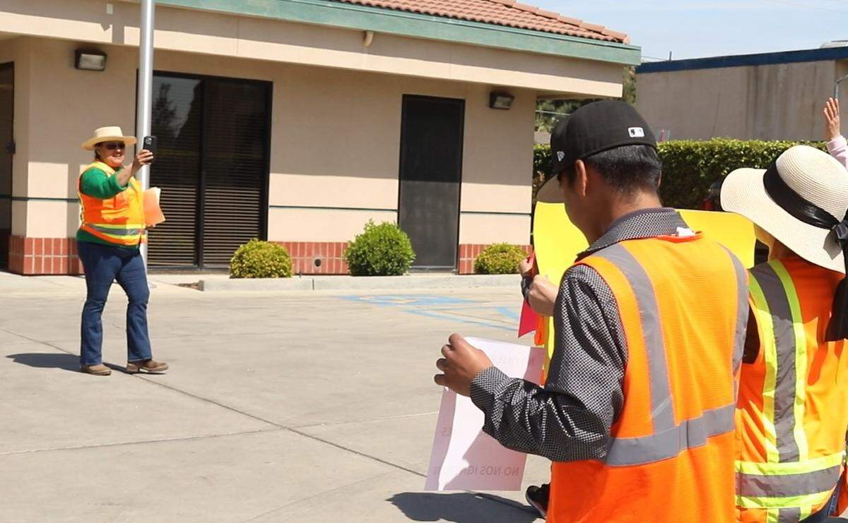 Maria Ester Gutierrez, in a dark green long sleeve shirt and sun hat, is seen leading the anti-union protest at the ALRB office in Visalia on March 27, 2024.