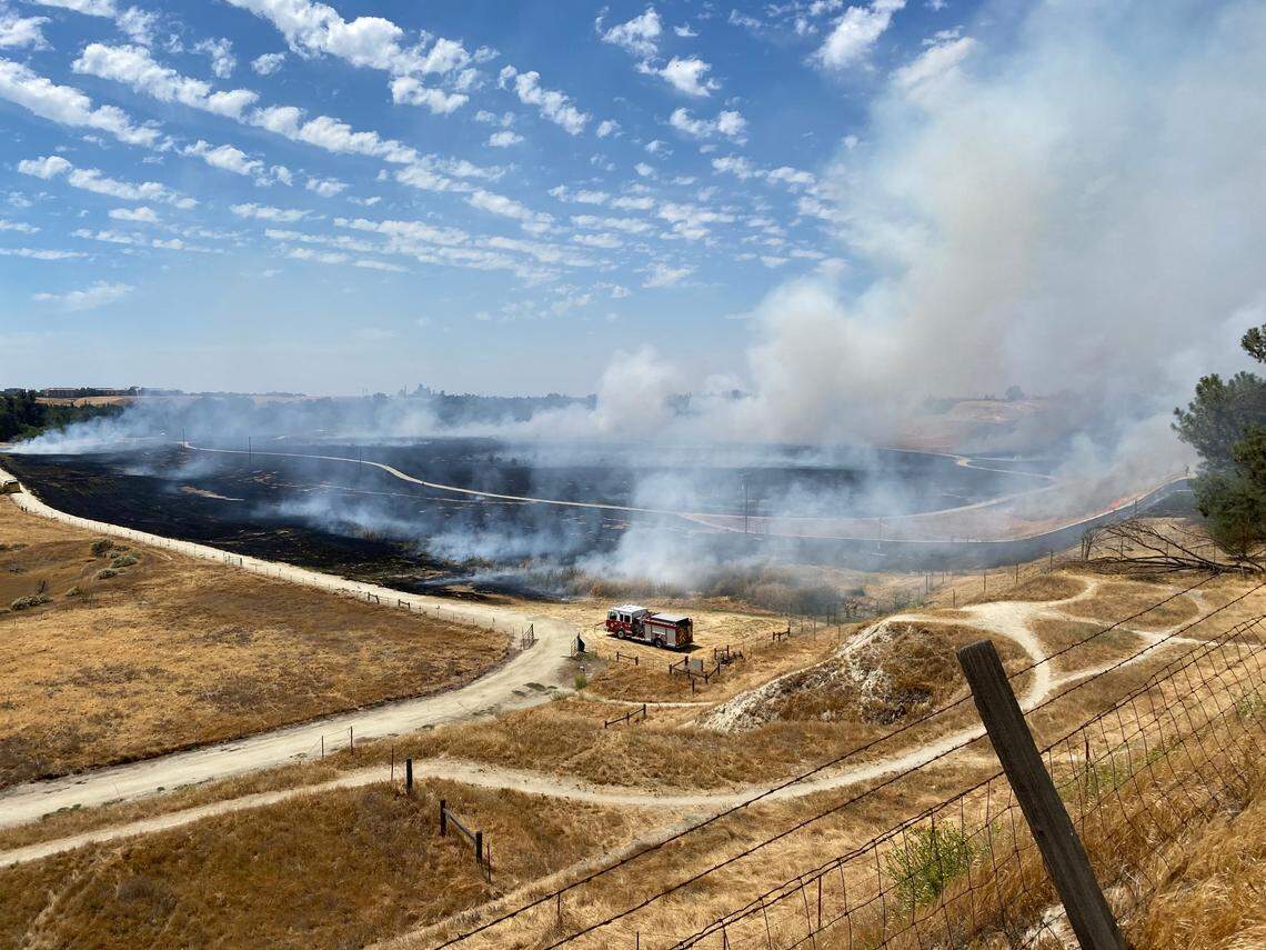 Crews battle a brush fire near Woodward Park in Fresno, CA, on Saturday, July 3, 2021.
