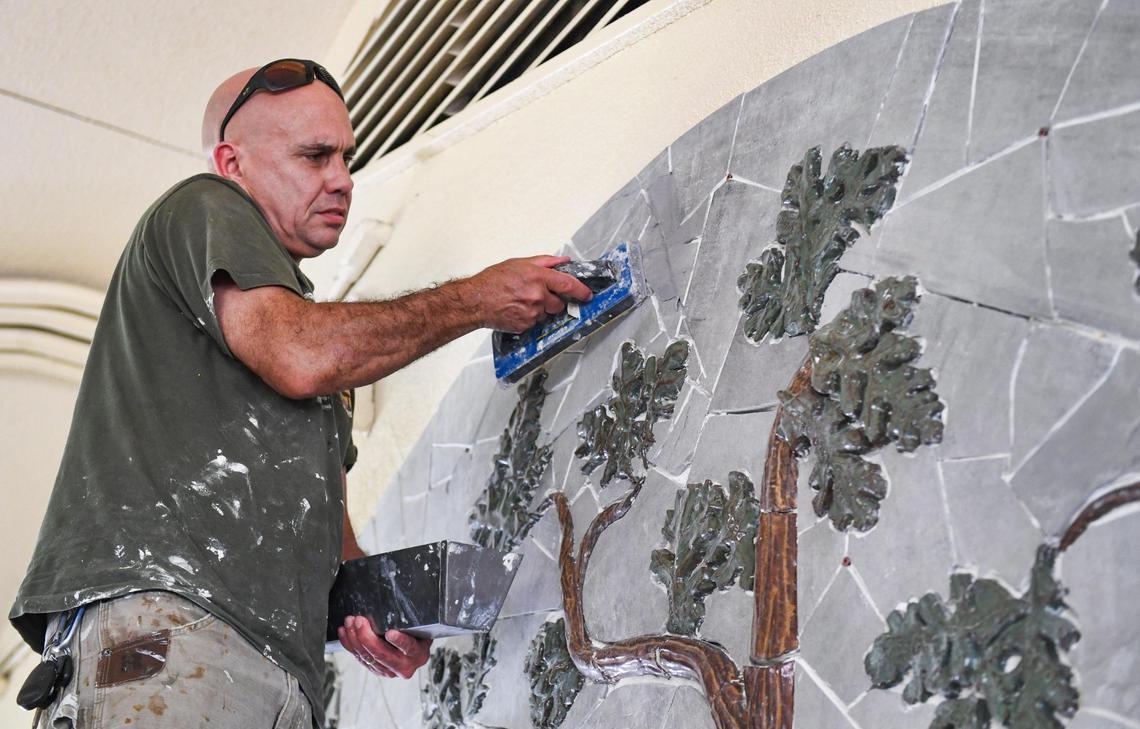 Artist David Roberts applies grout to a bas-relief and mosaic mural of a valley oak tree made by himself and sixth graders at Manchester GATE Elementary School in Fresno, on Tuesday, June 1, 2021.