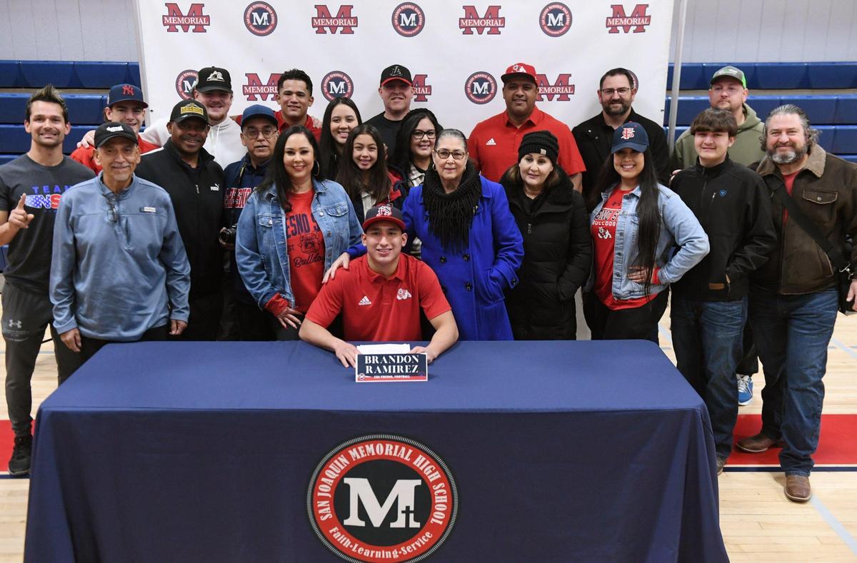 San Joaquin Memorial’s Brandon Ramirez, center foreground, seen with his family after a signing ceremony to Fresno State Wednesday, Dec. 21, 2022 in Fresno. Ramirez is The Bee’s Player of the Year.