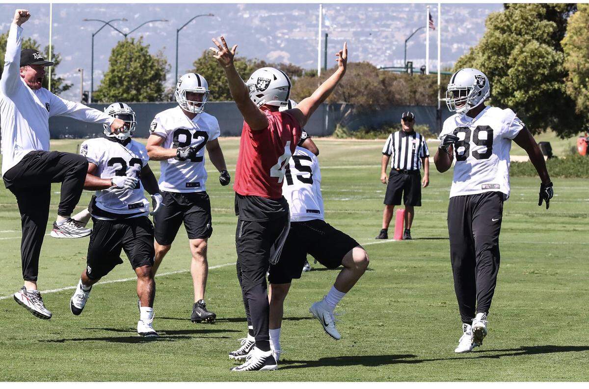 Jon Gruden leaps in the air as Derek Carr (red jersey), Amari Cooper (89), DeAndre Washington (33), Jordy Nelson (82) and Ryan Switzer (15) join a celebration during minicamp in Alameda.