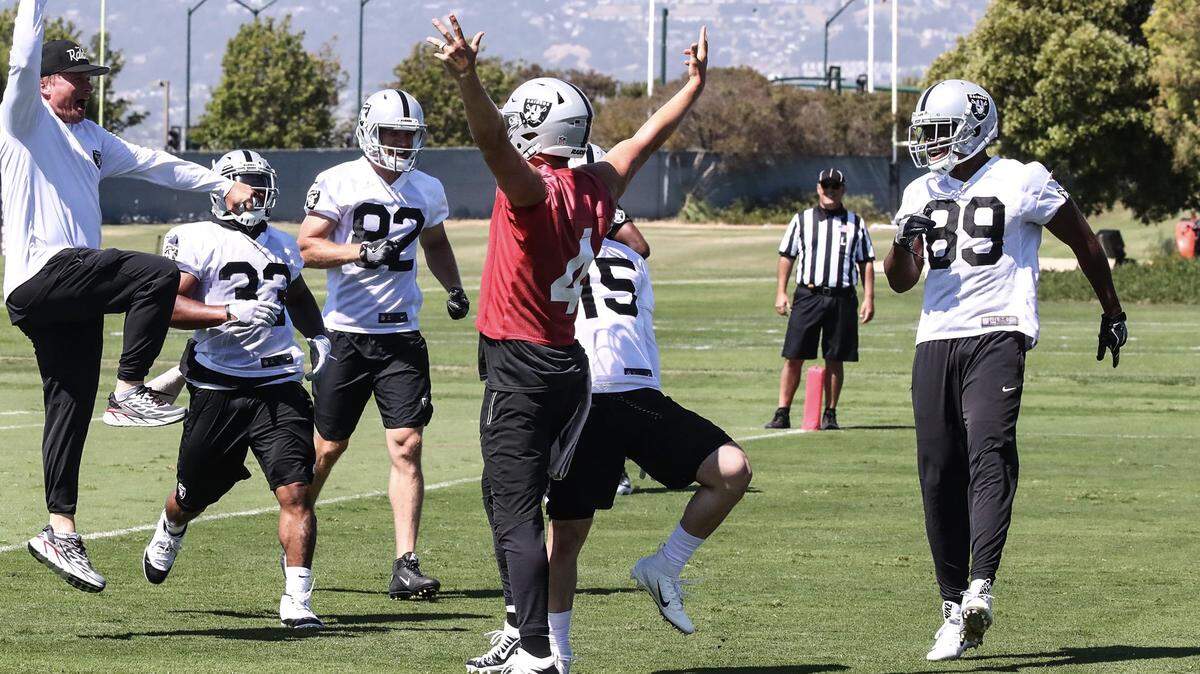 Jon Gruden leaps in the air as Derek Carr (red jersey), Amari Cooper (89), DeAndre Washington (33), Jordy Nelson (82) and Ryan Switzer (15) join a celebration during minicamp in Alameda.
