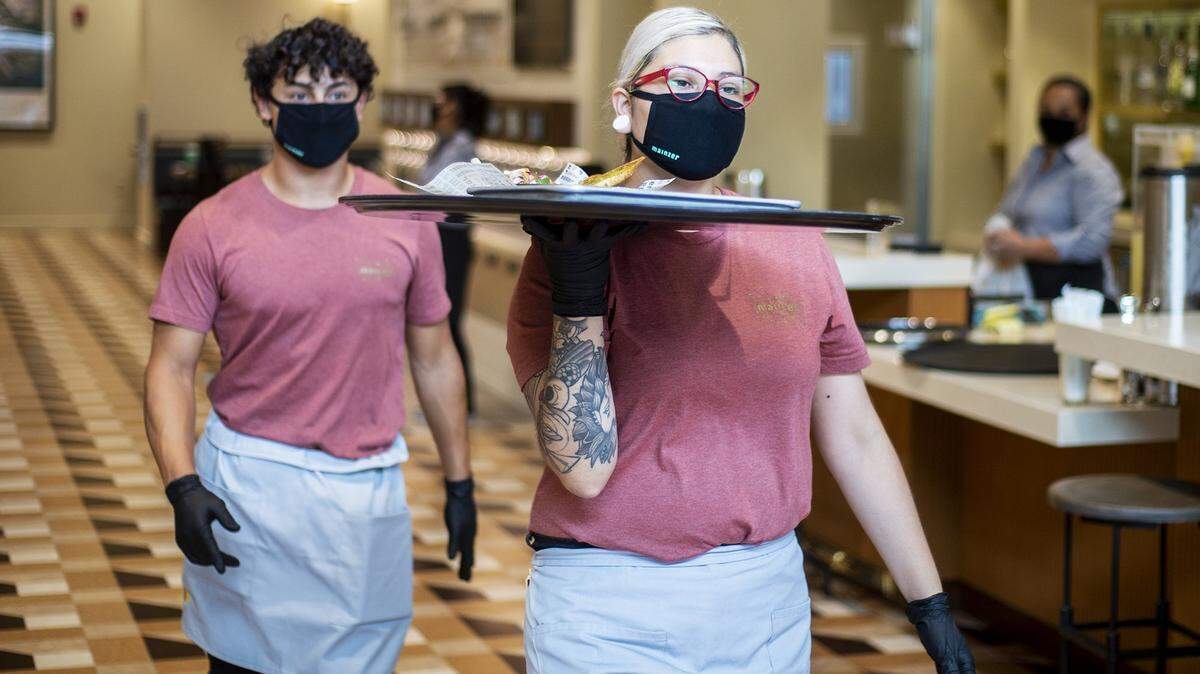Liz Alvarez, 29, of Merced, right, carries an order during a trial service at the restaurant inside the Mainzer Theater in Merced, Calif., on Thursday, Aug. 13, 2020.