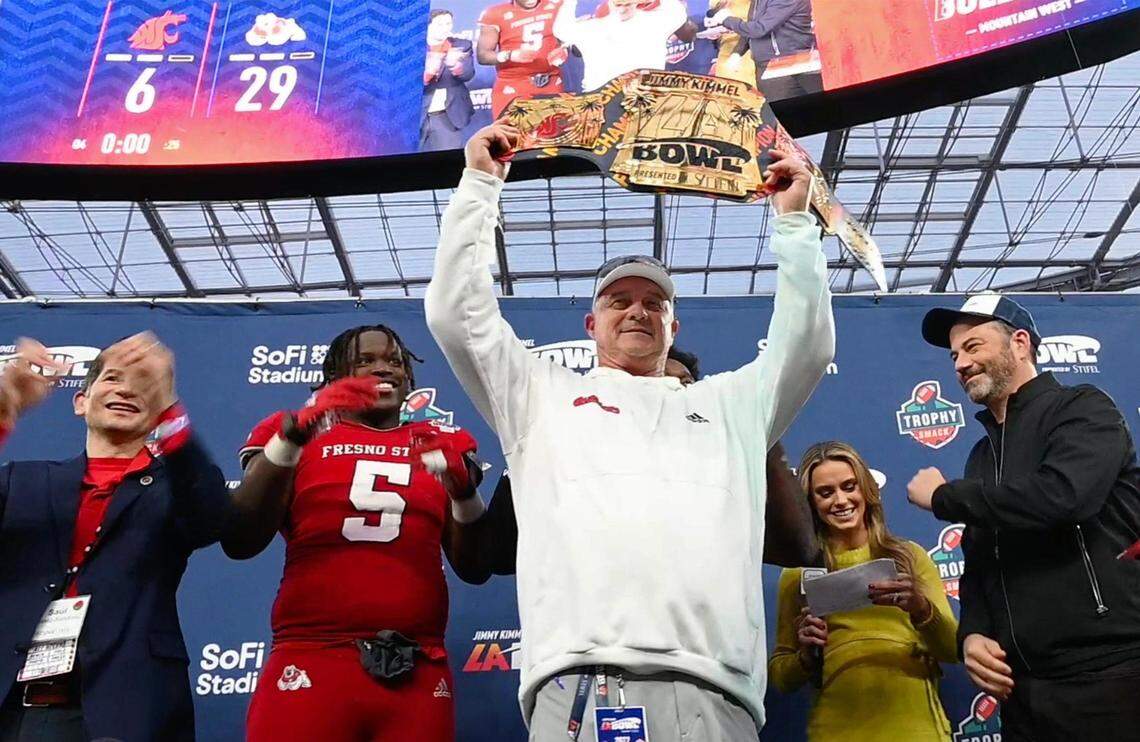 Fresno State head coach Jeff Tedford, center, lifts the championship belt after Fresno State defeated Washington State 29-6 at the Jimmy Kimmel LA Bowl Saturday, Dec. 17, 2022 in Inglewood, CA. Joining the celebration, from left,  Fresno State President Saúl Jiménez-Sandoval, game MVPs defensive lineman Devo Bridges and (behind Tedford) running back Jordan Mims, ABC on-field reporter Molly McGrath and Kimmel.