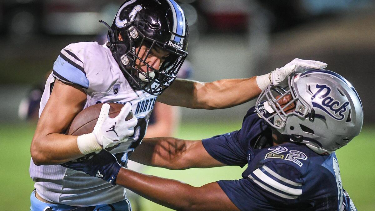 Clovis North’s Andrew Chavez, left, stiff-arms his way around a tackle attempt from Clovis East’s Cherub Adeniran during their TRAC opener at Lamonica Stadium on Friday, Sept. 29, 2023.
